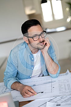 Thoughtful young architect man holding hand on chin and looking away