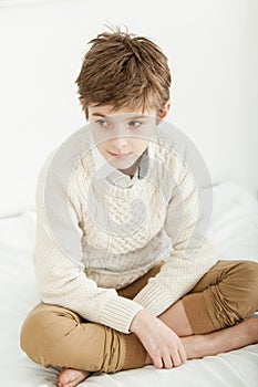 Thoughtful young boy sitting on his bed