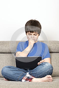 Thoughtful young boy and a tablet digital