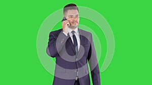 Thoughtful young businessman in suit and tie making several calls quickly on a Green Screen, Chroma Key.