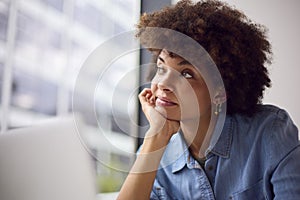 Thoughtful Young Businesswoman In Modern Office Working On Laptop Using Wireless Headset