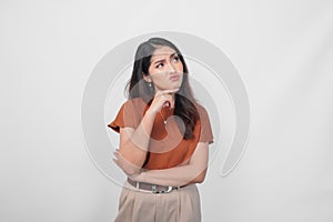 Thoughtful young casual girl wearing a brown shirt making serious expression isolated over white background