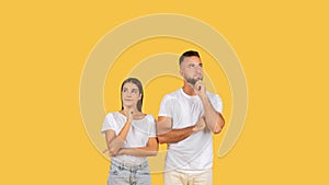 Thoughtful young couple in white t-shirts, with contemplative expressions, standing side by side