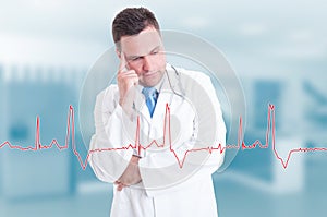 Thoughtful young doctor with heartbeat graph on screen