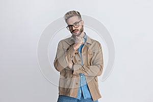 Thoughtful young guy in denim shirt holding hand to chin and thinking