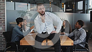 Thoughtful young guy looking away sitting on table in office serious man thinks about solving problem businessman makes