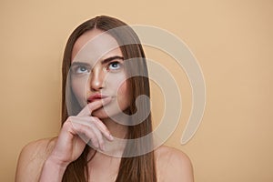 Thoughtful young lady touching her lips and looking up