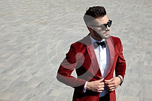 Thoughtful young man arranging red velvet tuxedo