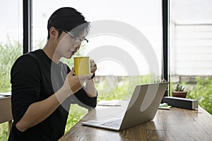 Thoughtful man entrepreneur drinking hot coffee and reading news on laptop computer.