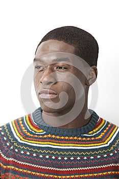 Thoughtful young man in knitwear looking away against white background