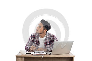 Thoughtful young man looking away while sitting at his working