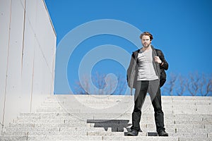 Thoughtful young man sitting on steps against blue sky background