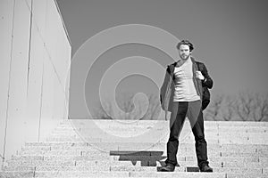 Thoughtful young man sitting on steps against blue sky background