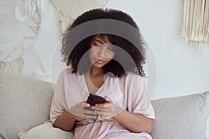 Thoughtful young mixed raced woman using smartphone enjoying chatting with boyfriend