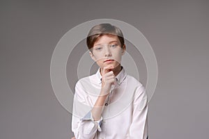 Thoughtful young teen man holding hand on chin indecision pose in white shirt