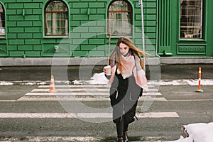Thoughtful young woman crossing city street in winter