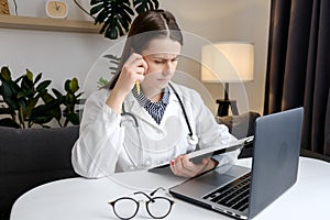 Thoughtful young woman doctor look at office computer screen ponder on establishing correct diagnosis choose treatment. Hard