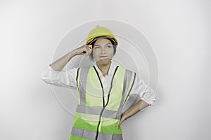 A thoughtful young woman labor worker wearing safety helmet and vest is looking aside to an idea on copy space , isolated by white