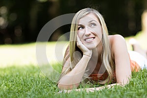 Thoughtful young woman lying on the grass