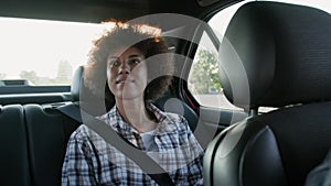 Thoughtful young woman sitting in the backseat of a car. Slow motion