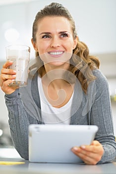 Thoughtful young woman with smoothie using tablet pc