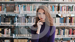 Thoughtful young woman stands before the shelves in the library