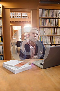 Thoughtful young woman using laptop in library