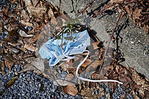 Thoughtlessly thrown away protective mask against SARS-Covid-19, which is lying on the ground as garbage by the roadside