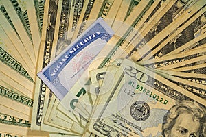 Social security card among thousands of US dollar bills photo