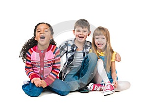 Thre cheerful kids sitting on the floor in a studio