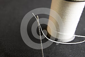 Thread in needle eye with spool on black