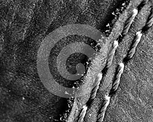 Thread seam on black leather material as background
