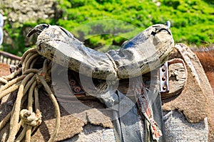 Threadbare old saddle on a shepherd`s horse, handmade saddle of a peasant shepherd