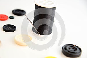 Threaded needle, black thread spool and buttons