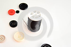 Threaded needle, black thread spool and buttons