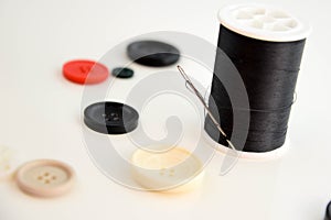 Threaded needle, black thread spool and buttons