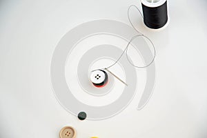 Threaded needle, buttons, and black spool of thread