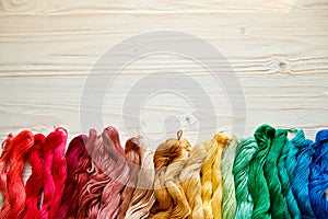 Threads for embroidery on a white wooden surface.