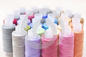 threads on spools of different colors lie on a light wooden table. Sewing and atelier hobby