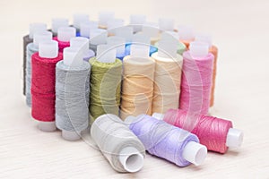threads on spools of different colors on a light wooden table. Three spools of thread are lying. Sewing and atelier hobb