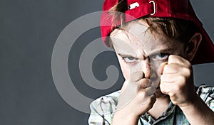Threatening boy with freckles and red hat back looking violent