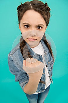 Threatening with fist. Angry child shake fist grey background. Beauty look of child girl. Small child in casual wear