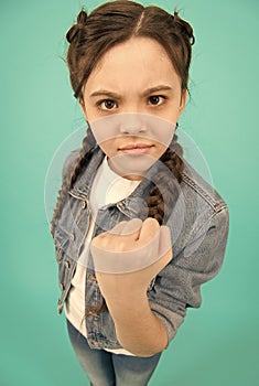 Threatening with fist. Angry child shake fist grey background. Beauty look of child girl. Small child in casual wear