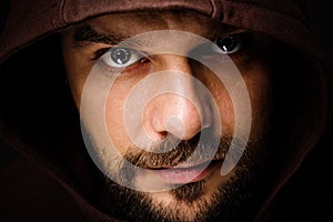 Threatening man with beard wearing a hood