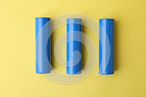 Three AA cell batteries on yellow background, top view