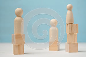 Three abstract wooden figures of people stand on different levels