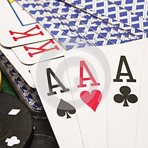 Three aces closeup against a deck of playing cards