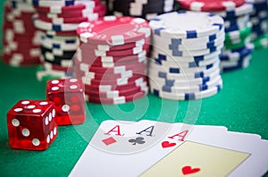 Three aces and red cubes with poker chips on green table