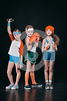 Three active kids in sportswear posing with sport equipment