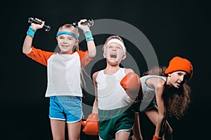 Three active kids in sportswear posing with sport equipment